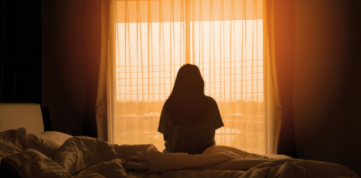 Anonymous female sat on a bed.