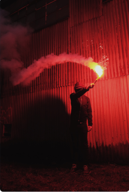 Image of a male holding up a red pyro device