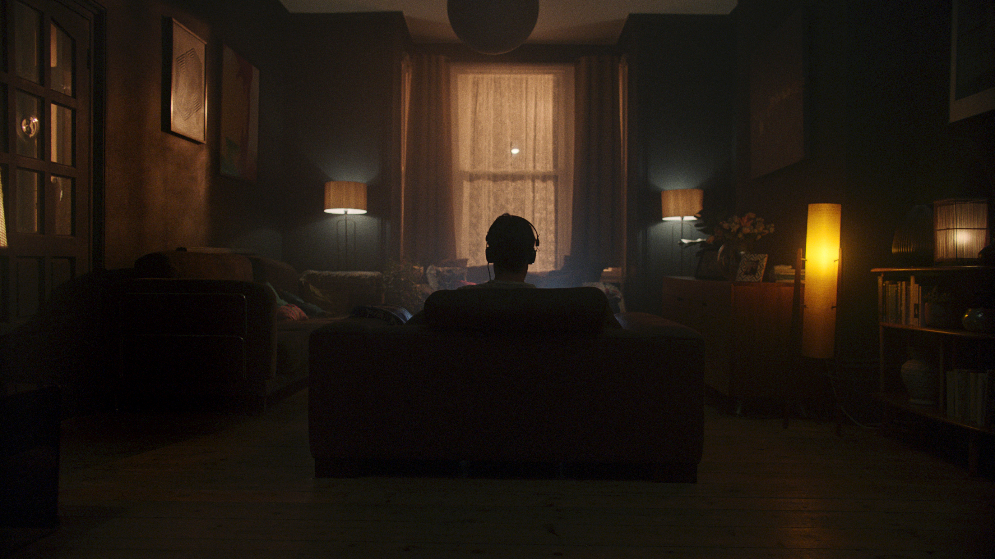 A man sitting in a darkened room in front of his laptop.